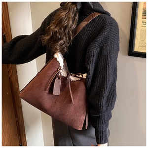 Dettaglio della grande borsa tote in pelle scamosciata marrone con bordo in pile sulla modella