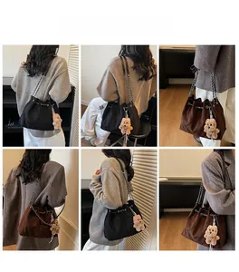 Detail view of large quilted chain bucket bag in black and brown with plush bear charm