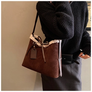 Close-up of brown suede hobo bag with white faux fur trim and bow detail on the shoulder strap