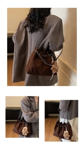 Detail of vintage quilted brown suede bucket bag featuring silver chain and plush bear charm