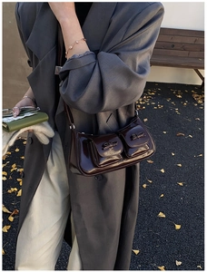 Deep burgundy glossy patent leather bag with bow pockets in an autumn street setting