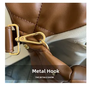 Close-up of golden metal hook and herringbone fabric lining on brown leather bag