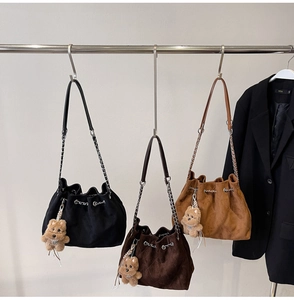 Three suede drawstring bucket bags with chain straps in black, coffee, and khaki colors
