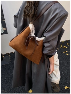 Brown suede shoulder bag with white faux fur trim shown on model in autumn street setting
