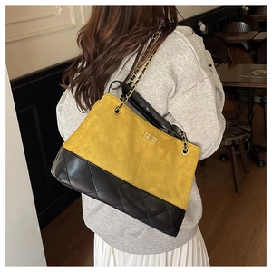 Detail view of quilted black leather and yellow suede cross-body bag with chain strap