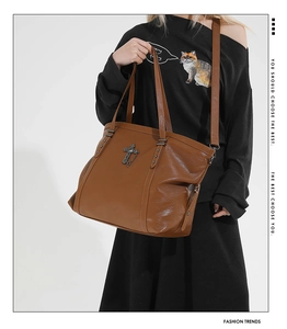 Close-up of vintage brown tote bag with metal cross pendant and star rivet details