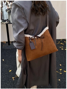 Close-up of brown suede shoulder bag with fleece trim and bow detail in autumn setting