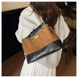 Detail of diamond quilted texture and golden chain on a two-tone suede shoulder bag