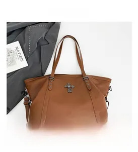 Close-up of brown leather tote bag featuring a vintage cross charm and star rivet accents