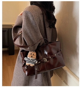 Détail d'un grand cabas marron foncé en cuir brillant avec breloque ours et œillets dorés