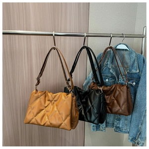 Quilted tote bags in yellow, black, and dark coffee hanging on hooks for display