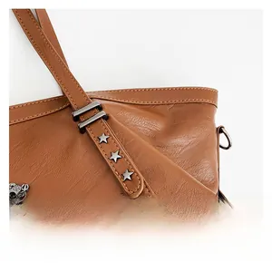 Close-up of brown leather tote featuring star rivets and metallic chain link detail