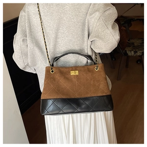 Detail of diamond-quilted brown suede and black leather shoulder bag with gold chain