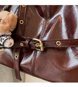 Detail of oil wax leather tote with gold hardware and a cute plush bear charm