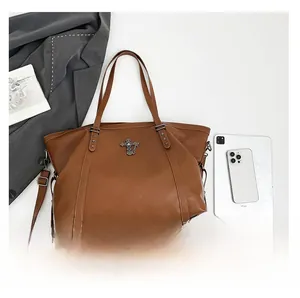 Detail of brown PU leather tote bag featuring metal cross pendant and star rivet accents