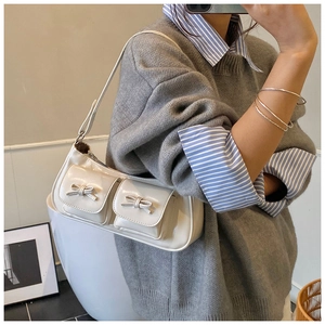 Detail of cream white faux leather underarm bag with decorative bows and double front pockets