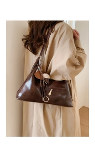 Détail d'un sac cabas vintage marron foncé avec fermetures dorées et breloques douces