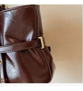 Detail of dark brown oil wax leather tote with gold buckle and pleated texture