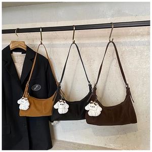 Detailed close-up of crescent shoulder bags in brown, black and coffee with cute plush pendants