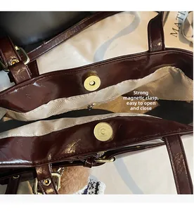 Detail of dark burgundy patent leather tote with magnetic closure and herringbone lining