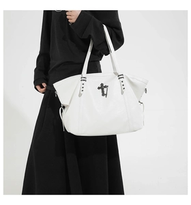 Macro detail of white gothic tote bag featuring black metal cross and star stud accents