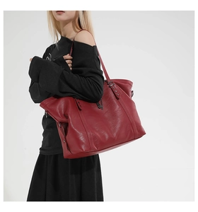 Detail of dark red oil wax leather tote bag with metallic rivet accents on shoulder strap