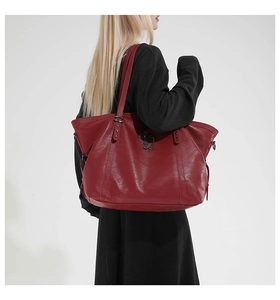 Close-up of burgundy tote bag featuring gothic metal cross and chain strap details