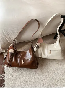 Détail des sacs hobo rétro en marron et beige avec finition brillante et breloques
