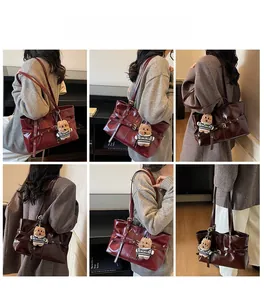 Détails d'un sac cabas en cuir ciré bordeaux avec un pendentif ours porté par un mannequin