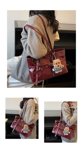 Detail of dark red oil wax leather tote bag featuring side buckle and teddy bear charm