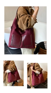 Makroaufnahme der burgunderroten Wildleder-Einkaufstasche mit Nieten und stylischen Taschen