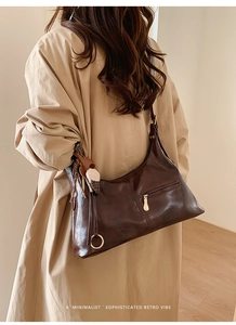 Détail du sac hobo en cuir marron avec breloque à gland et fermeture éclair dorée élégante