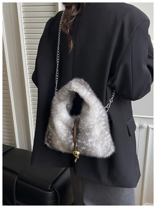 Detail view of plush faux fur shoulder bag with chain strap and gold sphere charm