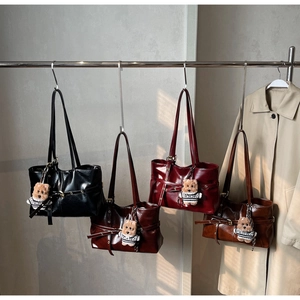 Detail showing various colors of pleated tote bags with cute bear charms on a rack