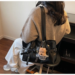 Détail du sac cabas en cuir ciré avec un pendentif chien en peluche et des œillets argentés