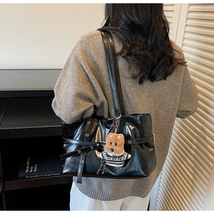 Détail du cabas en cuir ciré noir avec ceinture à œillets et pendentif chien mignon