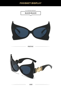 Detail view of bat-wing sunglasses with golden round metal relief on the black frame