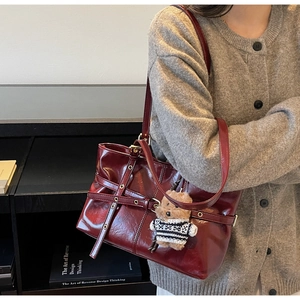 Détail du cabas en cuir ciré bordeaux avec boucle décorative et breloque en ours