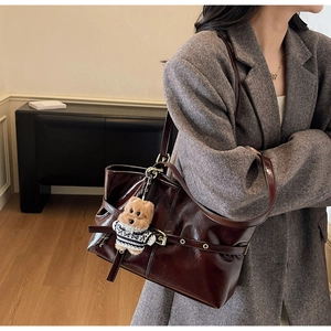 Détail du sac cabas en cuir ciré bordeaux avec un charmant accessoire ours en peluche