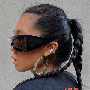 Detail of oversized black square sunglasses and silver hoop earrings on a model
