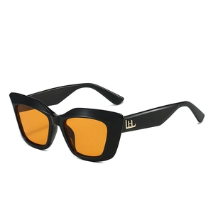Lunettes de soleil œil-de-chat à monture noire, verres orange et logos en métal