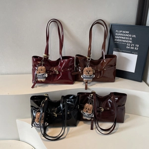 Quatre sacs cabas en cuir verni brillant avec pendentifs ours sur présentoir blanc