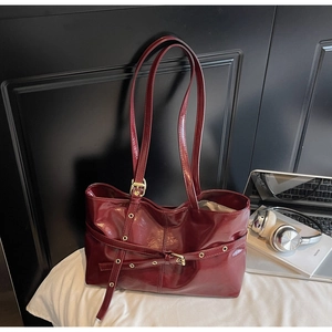 Détail du sac cabas bordeaux avec boucles métalliques dorées et œillets décoratifs