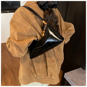 Détail du sac croissant en cuir verni noir brillant avec accents de chaîne dorée chic