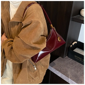 Vue détaillée du sac demi-lune en cuir verni bordeaux avec pendentif doré élégant
