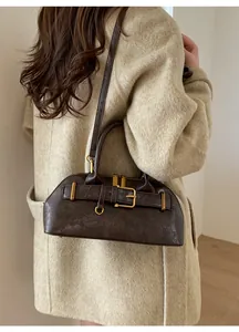 Close-up of brown vintage PU leather handbag with golden hardware worn by a model