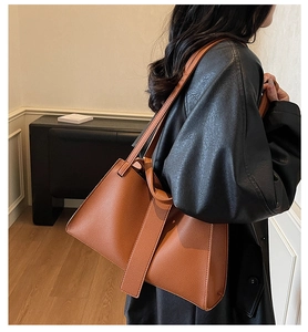 Close-up of caramel brown lychee grain leather tote bag worn on shoulder by a model