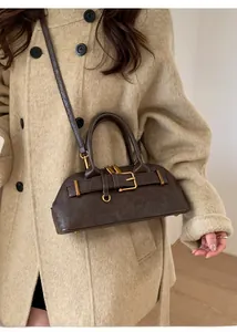 Detail of dark brown vintage faux leather handbag with decorative gold buckle and dual handles
