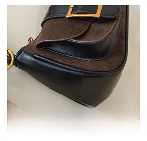 Detail of contrast stitching and gold buckle on the two-tone leather shoulder bag