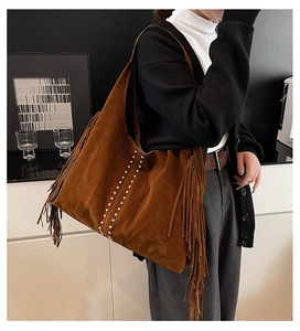 Detail of a brown suede hobo bag featuring long tassels and silver metal rivets decoration